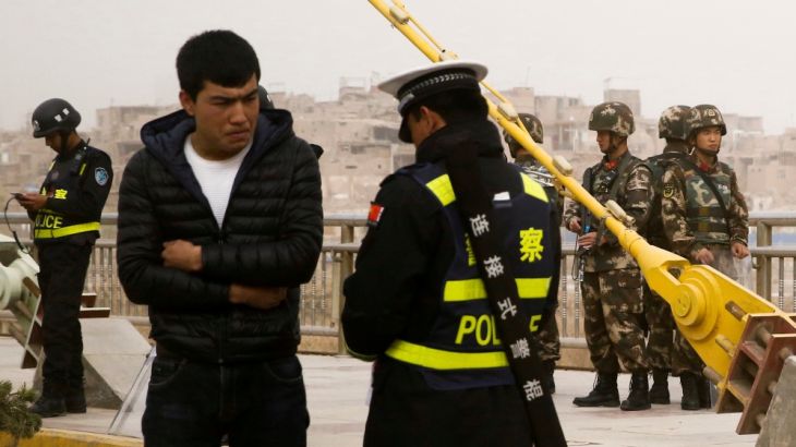 FILE PHOTO: A police officer checks the identity card of a man as security forces keep watch in a street in Kashgar