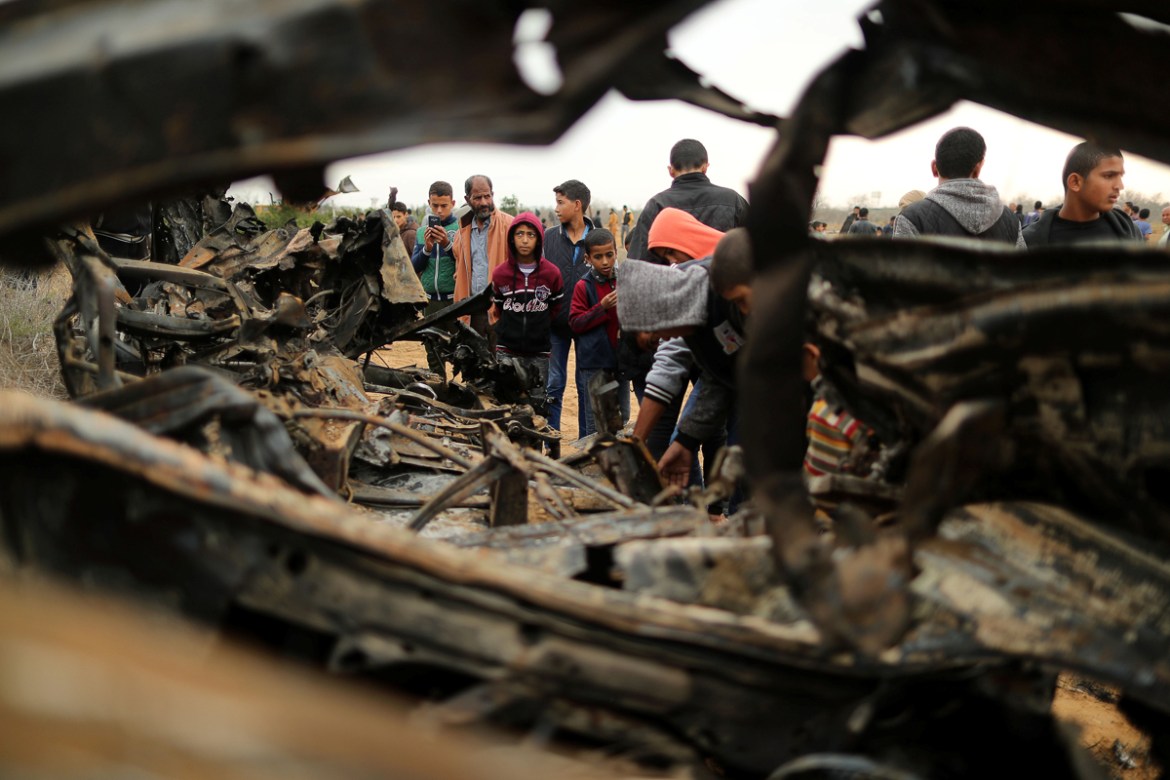 Palestinians gather around the remains of a vehicle that was destroyed in an Israeli air strike, in Khan Younis in the southern Gaza Strip November 12, 2018. REUTERS/Suhaib Salem -