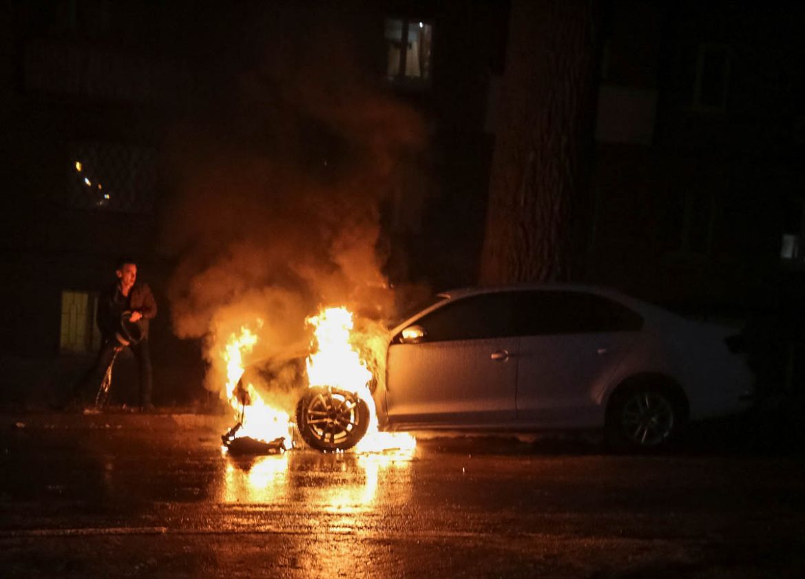 A man extinguishes a burning car of the embassy of Russia after a protest against the seizure by Russian special forces of three Ukrainian naval ships, which Russia blocked