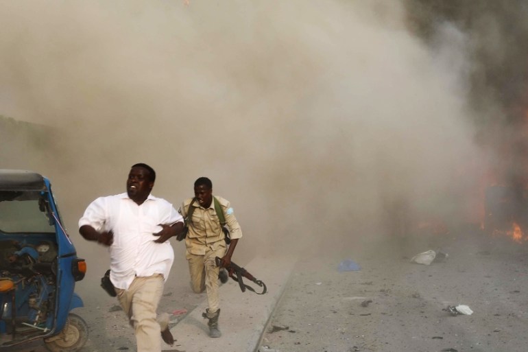 Somali security officers run from the scene of an explosion in Mogadishu