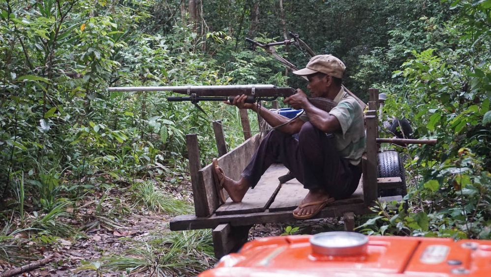 Lim plays with a crude rifle found at an illegal logging camp [Matt Blomberg/Al Jazeera]