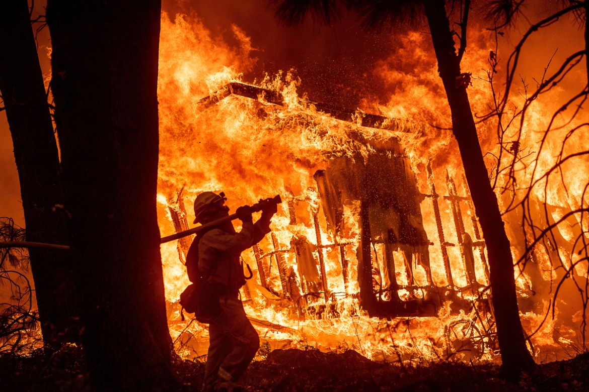 Firefighter Jose Corona sprays water as flames consume from the Camp Fire consume a home in Magalia, Calif., on Friday, Nov. 9, 2018. (AP Photo/Noah Berger)