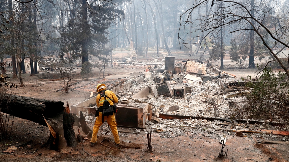 A firefighter extinguishes a hot spot in a neighbourhood destroyed by the Camp Fire in Paradise, California [Terray Sylvester/Reuters]
