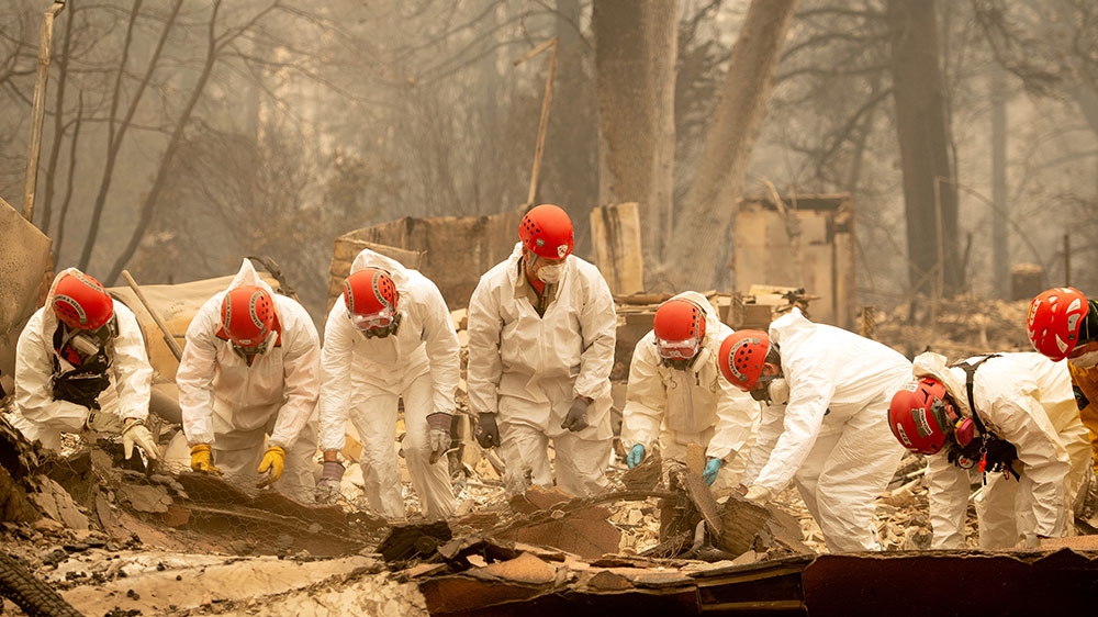 Rescue workers sift through rubble in search of human remains at a burned property in Paradise, California [Josh Edelson/Al Jazeera] 