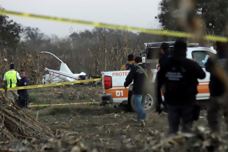 Police and rescue personnel stand at the scene where the helicopter transporting Martha Erika Alonso, governor of the state of Puebla, and his husband Senator Rafel Moreno Valle crashed, in Coronango