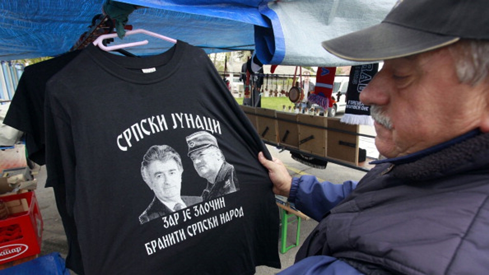 A Bosnian Serb vendor selling a T-shirt depicting convicted Serb war criminals Radovan Karadzic and Ratko Mladic. It reads 'Serb Heroes: Is It a Crime To Defend Serb People' [Milan Radulovic/AFP]