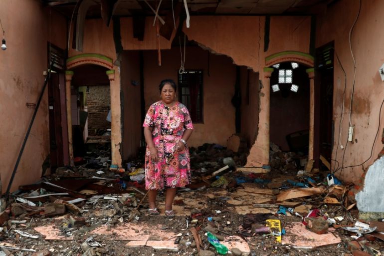 A woman stands among debris at an area affected by the tsunami in Labuhan