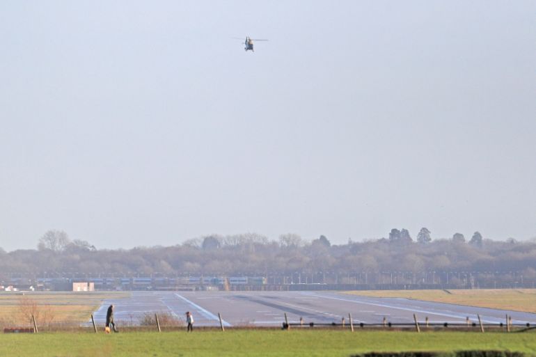A police helicopter flies over the closed runway at Gatwick Airport after drones flying illegally over the airfield forced the closure of the airport, in Gatwick