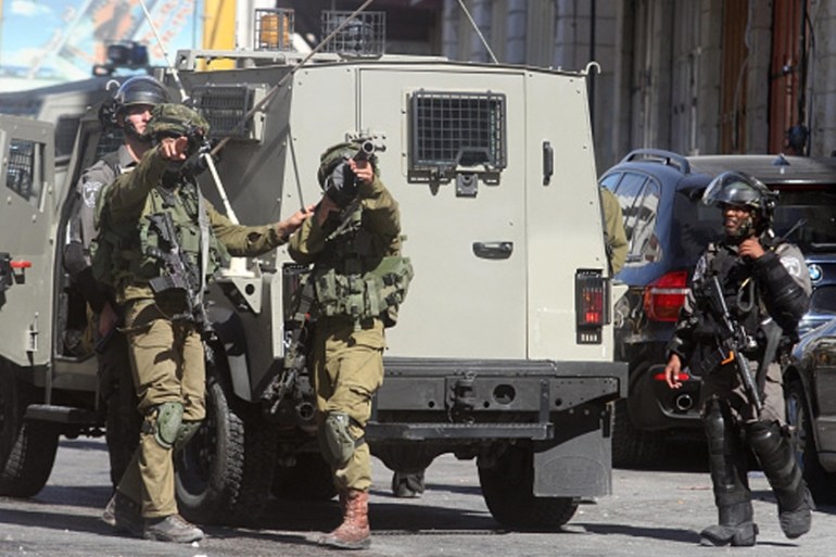 Conflicts between Israeli soldiers and Palestinian demonstrators in West Bank HEBRON, WEST BANK - SEPTEMBER 23: An Israeli soldier aims at Palestinian demonstrators in Hebron