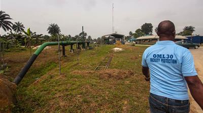 A pipeline protection official walks past crude export lines in Nigeria's Niger Delta area [Al Jazeera]