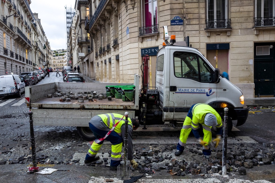Workers clean the destroyed pavement of a street where police forces clashed heavily with extremists groups during last Saturdayi´s protests near the Champs ElysE`es on December 03, 2018 in Paris, Fra