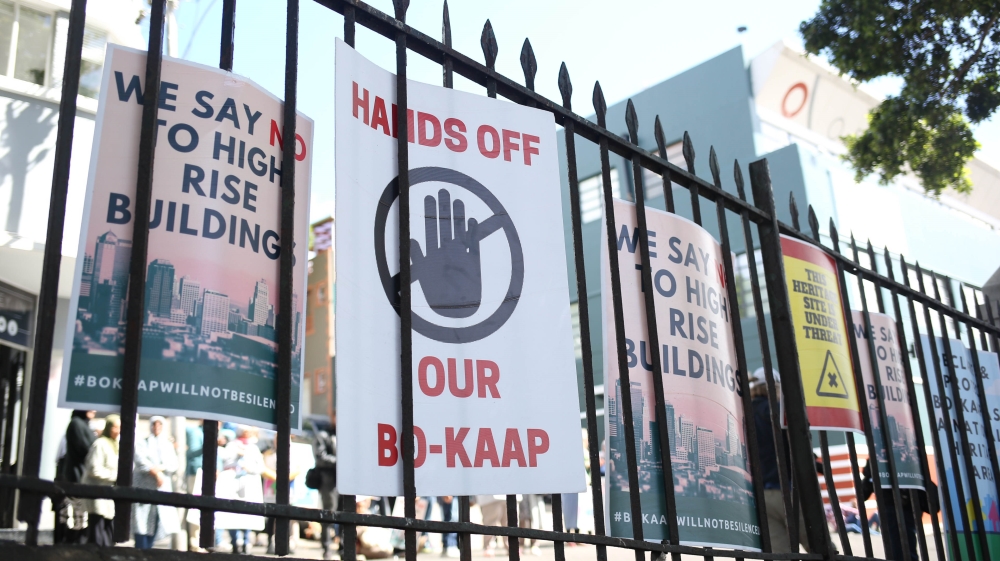Placards are tied to a railing at a protest in Bo Kaap [Erica Jenkin/Al Jazeera]