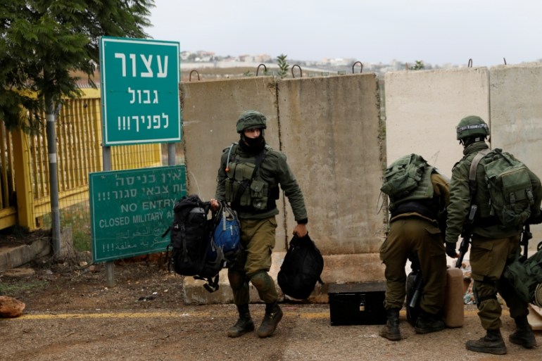 Israeli soldiers carry gear the morning after the Israeli military said it had launched an operation to "expose and thwart" cross-border attack tunnels from Lebanon, in Israel''s northernmost town Metu
