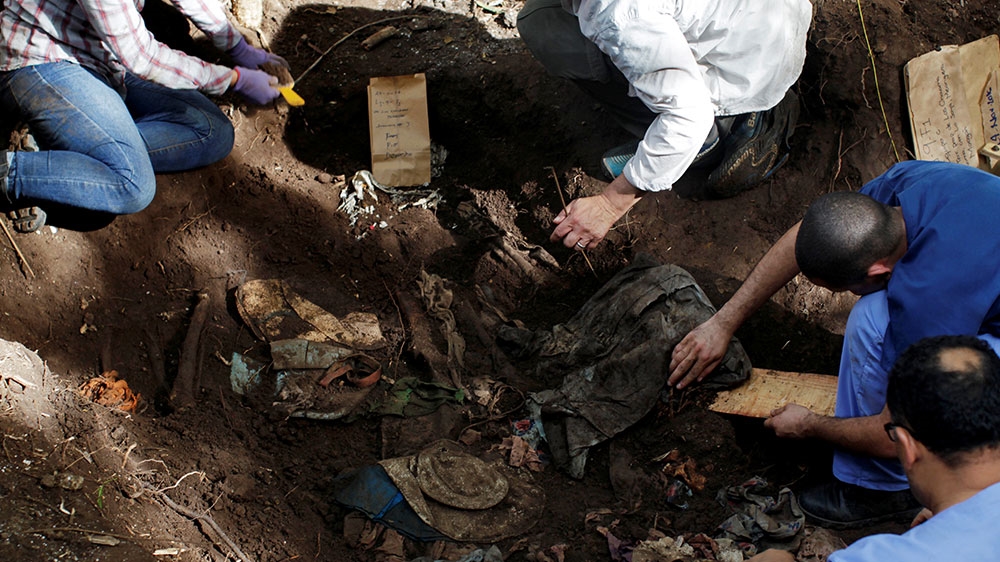 Members of the forensic team work at an exhumation site in the village of La Joya as they search for human remains of the El Mozote massacre in the town of Meanguera [File: Jose Cabezas/Reuters] 