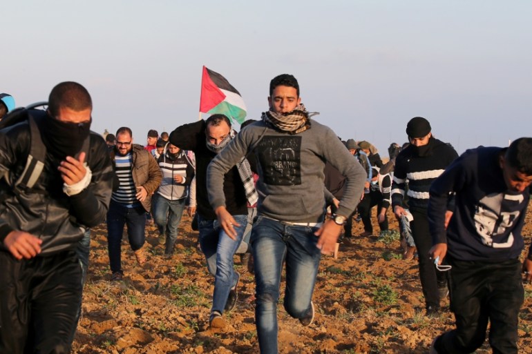 Palestinian demonstrators run for cover from Israeli gunfire and tear gas during a protest near the Israel-Gaza border fence, in the southern Gaza Strip