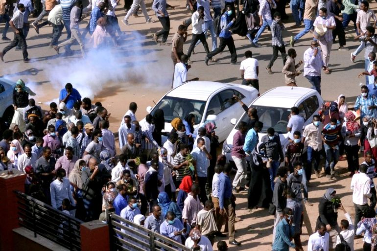 FILE PHOTO: Sudanese demonstrators run from teargas lobbed to disperse them as they march along the street during anti-government protests in Khartoum