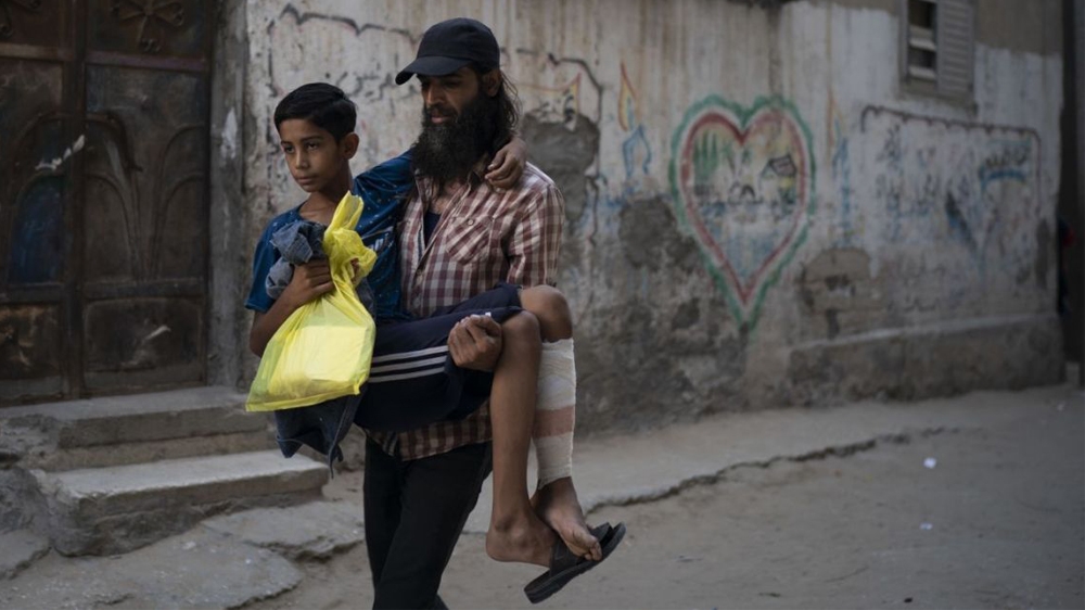 Raed Abu Khader, right, carries his 12-year-old son Mohammed as they return from the hospital in Gaza City [Associated Press]