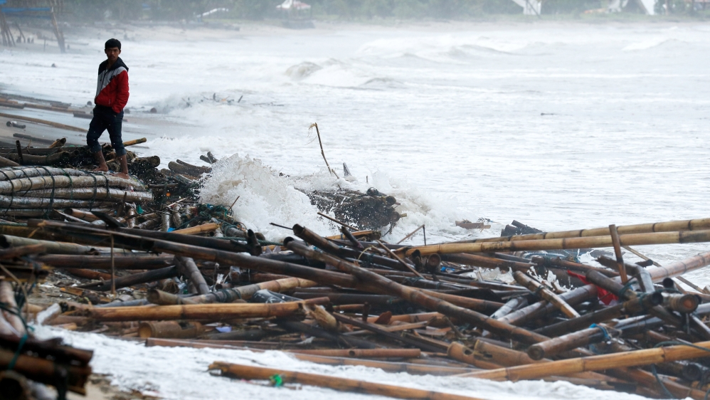 A resident affected by the tsunami stands next to debris in Carita beach [Jorge Silva/Reuters]