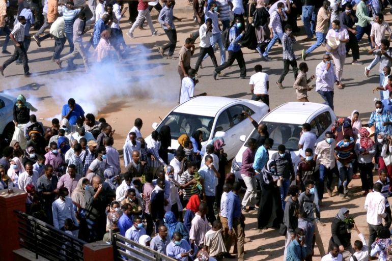 Sudanese demonstrators run from teargas lobbed to disperse them as they march along the street during anti-government protests in Khartoum