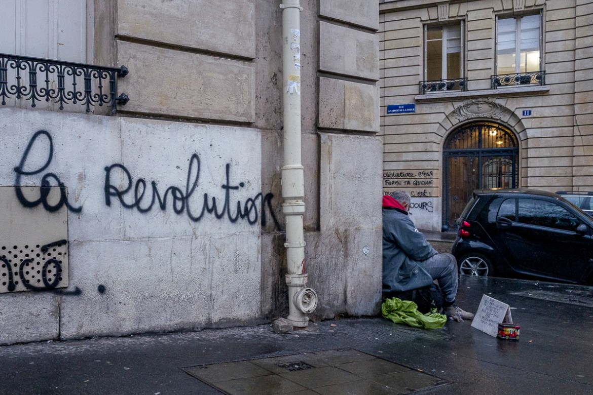 A man begs for money in front of a building where messages calling for revolution were written during last Saturdayi´s protests on December 03, 2018 in Paris, France. After the violent clashes of last