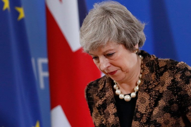British Prime Minister Theresa May walks by the Union Flag and EU flag as she departs a media conference at an EU summit in Brussels, Friday, Dec. 14, 2018. European Union leaders expressed deep doubt