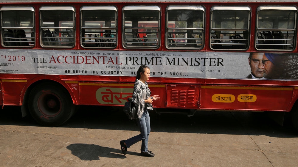 A woman walks past a bus featuring an advertisement for 'The Accidental Prime Minister' in Mumbai [Francis Mascarenhas/Reuters]