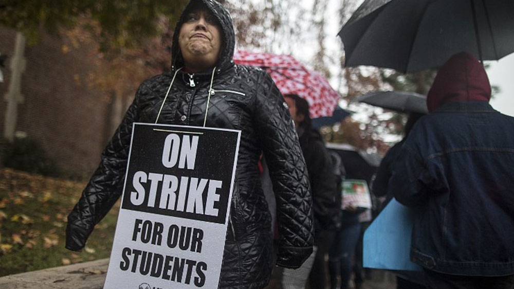 Teachers and students protest and picket in the pouring rain [Barbara Davidson/Getty Images/AFP] 