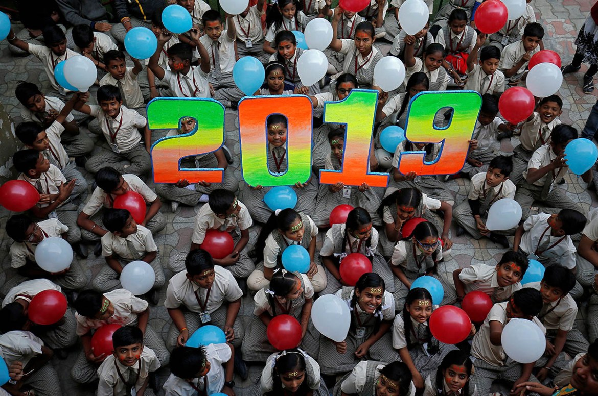 Schoolchildren hold balloons as they pose during celebrations to welcome the New Year at their school in Ahmedabad, India, December 31, 2018. REUTERS/Amit Dave