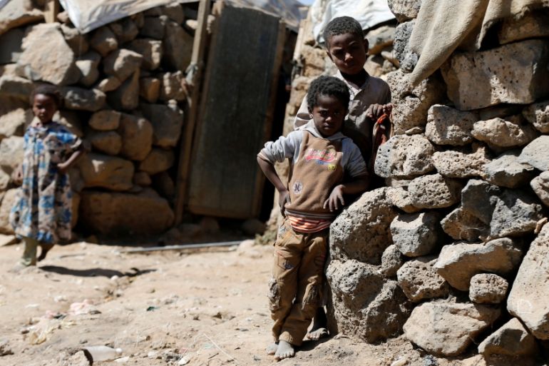 Children stand near their hut at a makeshift camp for internally displaced people near Sanaa, Yemen