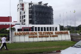 (FILES) In this file photo taken on June 16, 2017 people walk past the premises of the National Radio and Television centre in Libreville, after unknown assailants targeted several medias in the city.