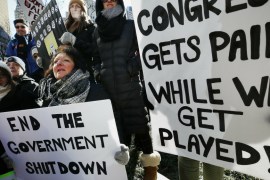 Government workers and their supporters hold signs during a protest in Boston