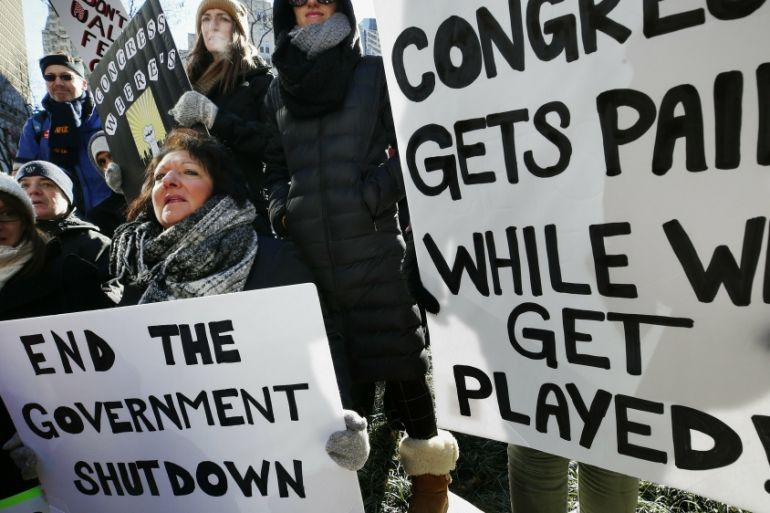 Government workers and their supporters hold signs during a protest in Boston