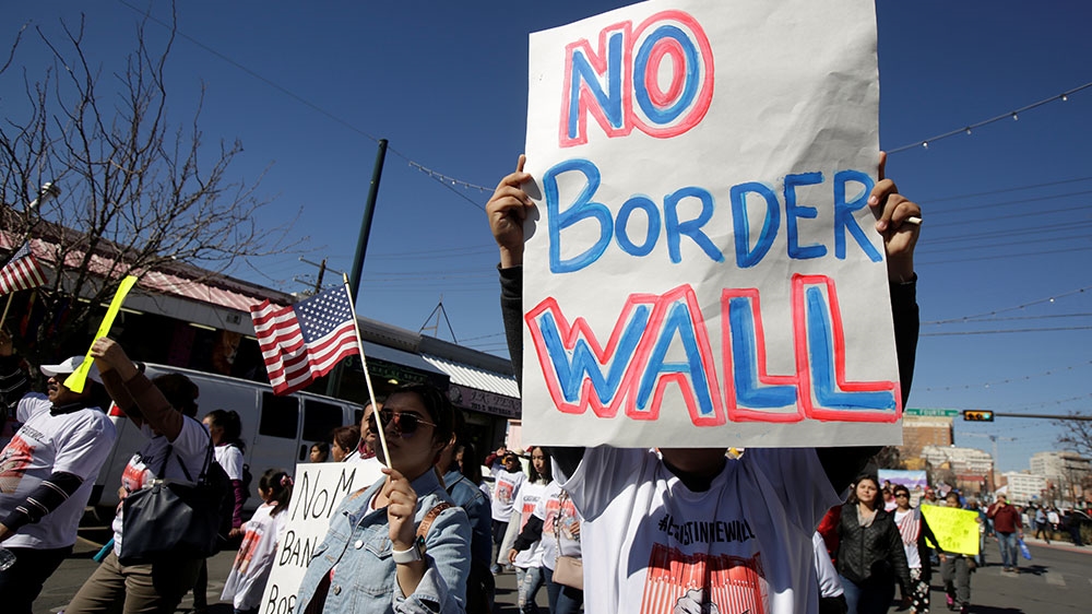 A man holds a sign during a march against building a wall on US-Mexico border [Jose Luis Gonzalez/Reuters] 