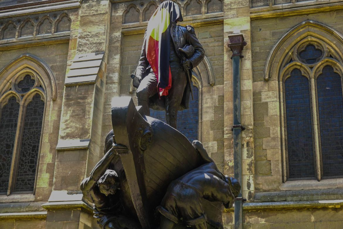 A statue of one of Melbourne’s founding colonialists Matthew Flinders is draped with the Aboriginal flag after the protest has finished.
