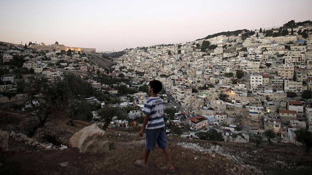 A Palestinian boy walks by the densely populated Palestinian neighbourhood of Silwan. Jewish settlers have been notching up property gains in the heart of Palestinian East Jerusalem through a series of indirect deals involving local frontmen or straw companies [Ahmad Gharabli/AFP]