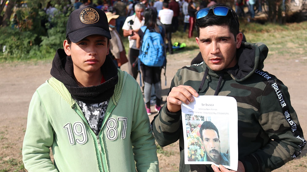 Javier Gonzalez Neri (right) holding a picture of the missing father of cousin Christopher Neri Carrillo (left) [Tim MacFarlan/Al Jazeera]