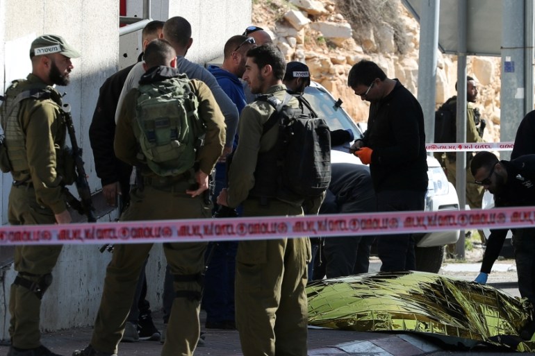 Israeli forces gather near the dead body of a Palestinian woman at the scene of an incident at a checkpoint, east of Jerusalem