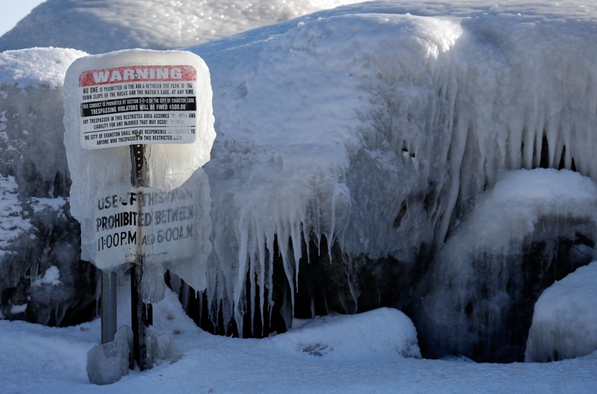 A warning sign is covered by ice at Clark Square park in Evanston, Ill., Wednesday, Jan. 30, 2019. A deadly arctic deep freeze enveloped the Midwest with record-breaking temperatures on Wednesday, tri
