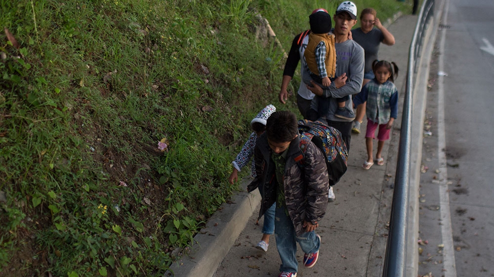 A family migrating with the Honduran caravan tails behind the rest of the group as it leaves San Pedro Sula [Jeff Abbott/Al Jazeera]