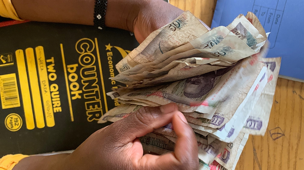 Miriam Okungu holds money collected from the group [William Worley/Al Jazeera]