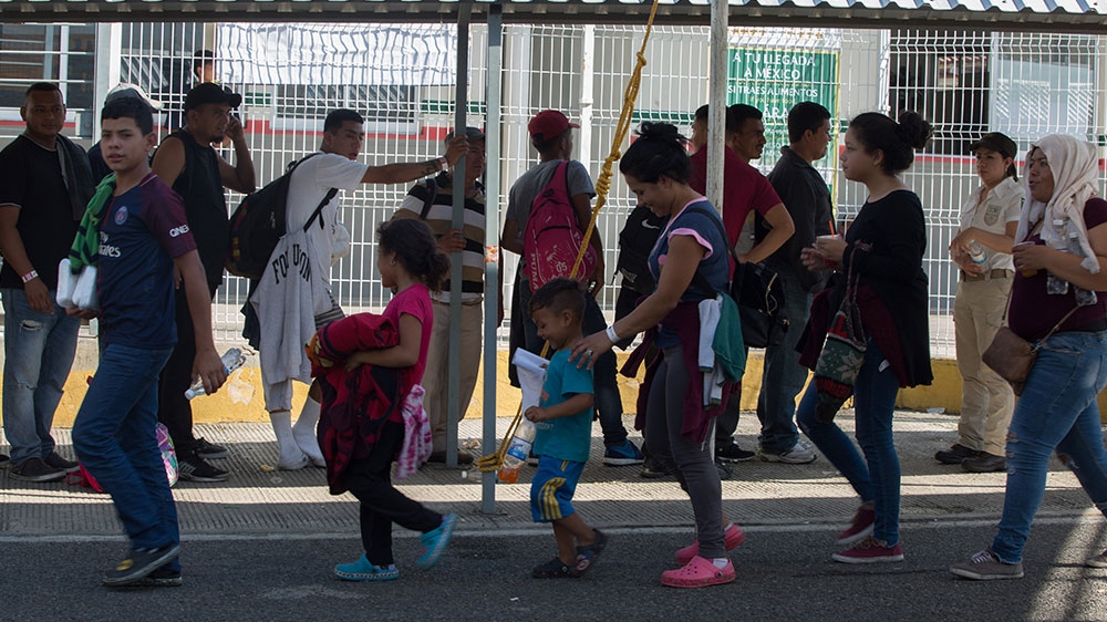 A group of asylum seekers follow a Mexican immigration official [Jeff Abbott/Al Jazeera] 