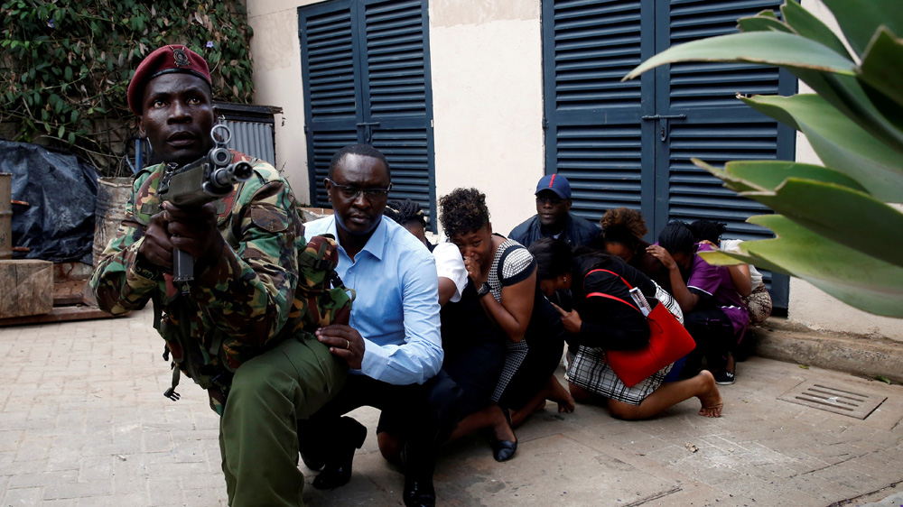 People are evacuated by a member of security forces during the al-Shabab attack in Nairobi [Baz Ratner/Reuters]