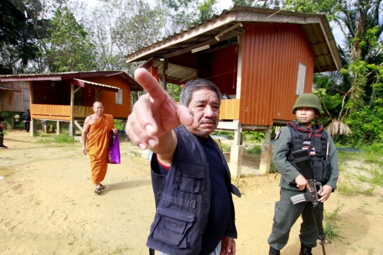 MilitaMilitary police officers and a buddhist monk are seen at a temple where unknown gunmen shot dead two Buddhist monks and injured two others on Friday in Su-ngai Padi district in the southern prov