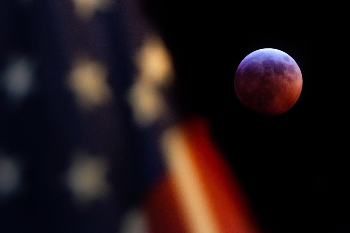 A U.S. Flag in downtown Washington flies in front of the moon during a lunar eclipse, Sunday, Jan. 20, 2019. The entire eclipse will exceed three hours. Totality - when the moon''s completely bathed in