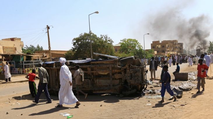 A police car flipped over and damaged by mourners is seen near the home of a demonstrator who died of a gunshot wound sustained during anti-government protests in Khartoum