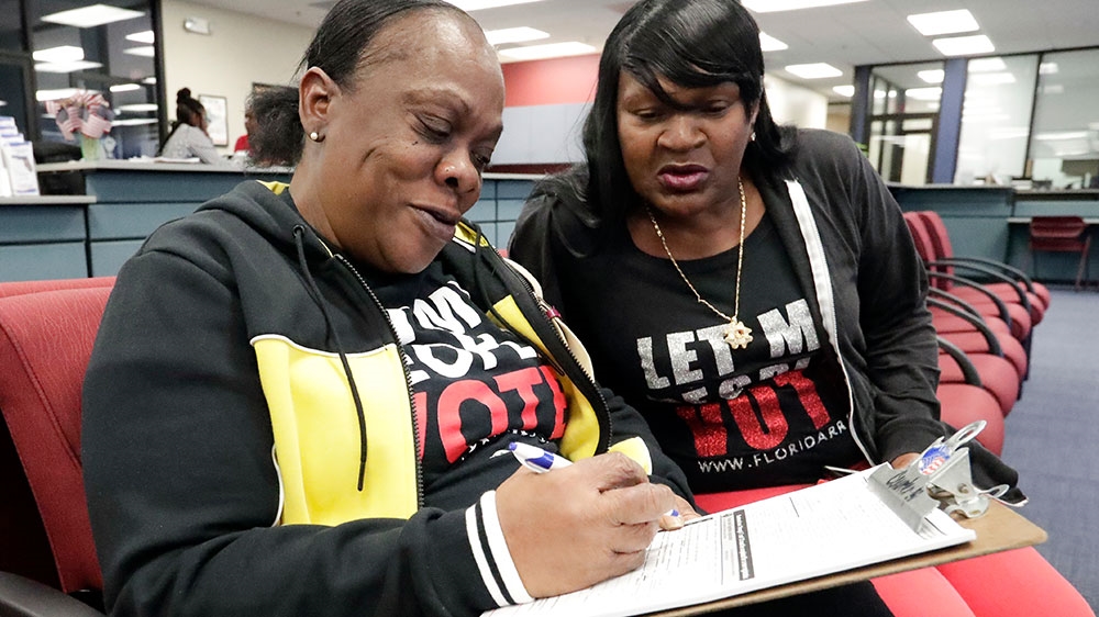 Former felon Yolanda Wilcox, left, fills out a voter registration form at the Supervisor of Elections in Orlando, Florida [John Raoux/AP Photo]