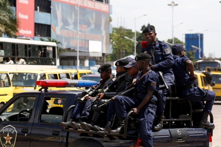 Congolese policemen drive past Congo''s Independent National Electoral Commission headquarters in Kinshasa