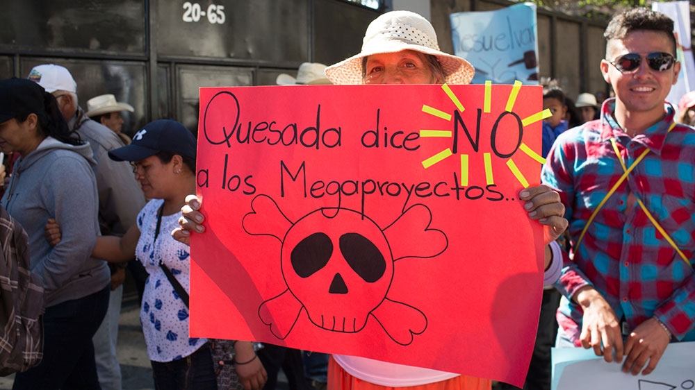 A woman carries a sign declaring 'Quesada Says No to Mega-Projects' [Jeff Abbott/Al Jazeera]