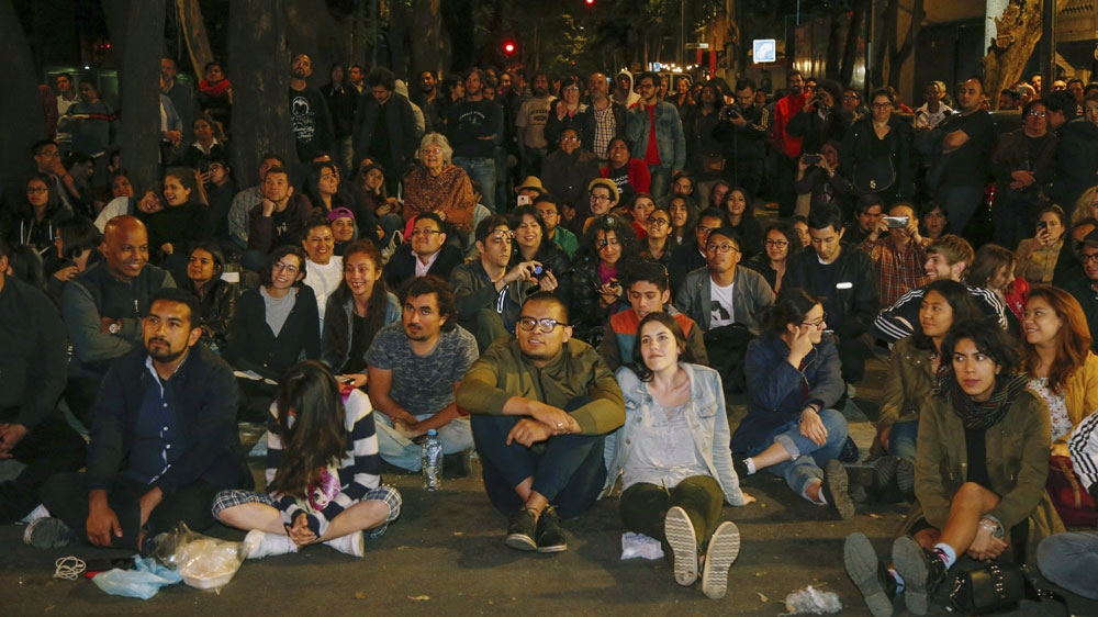 People watch the 91st Academy Awards, shown on a screen installed for a watch party in a plaza in the Roma neighbourhood of Mexico City [Anthony Vazquez/AP]