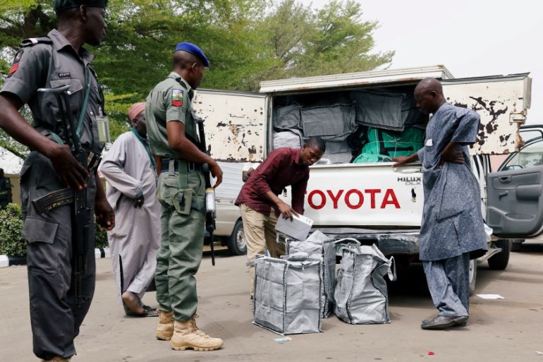 Police members oversee Ad-hoc staff loading boxes onto a truck during the distribution of election materials at the INEC office in Yola